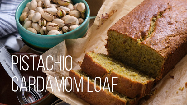 Loaf on a cutting board with pistachio nuts in a bowl.